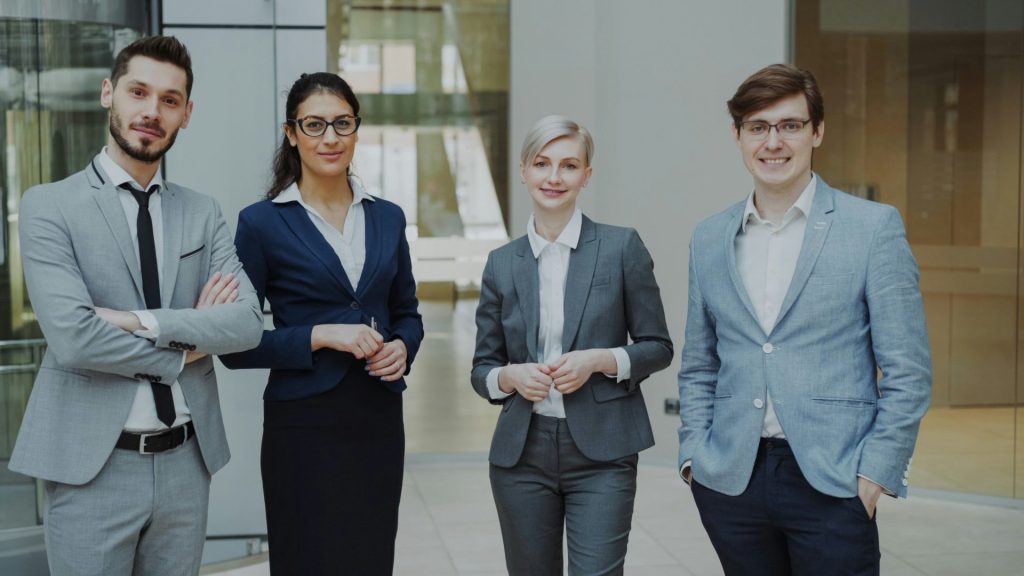 Four professionals in business attire stand together.